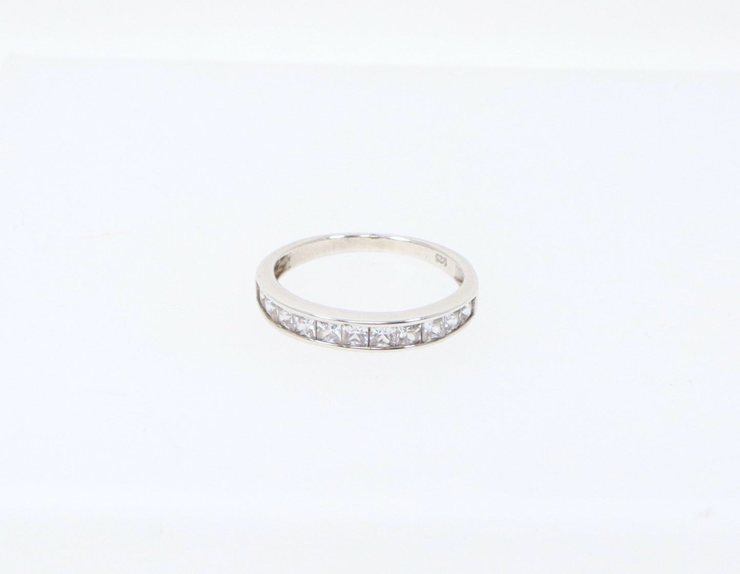 A sterling silver half eternity ring with 11 channel set princess cut cubic zirconia gemstones. Cubic Zirconia has all the style and elegance of a real diamonds, looks just like the genuine item, add some affordable sparkle. The ring is stamped 925 inside the band for sterling silver. UK finger size R.