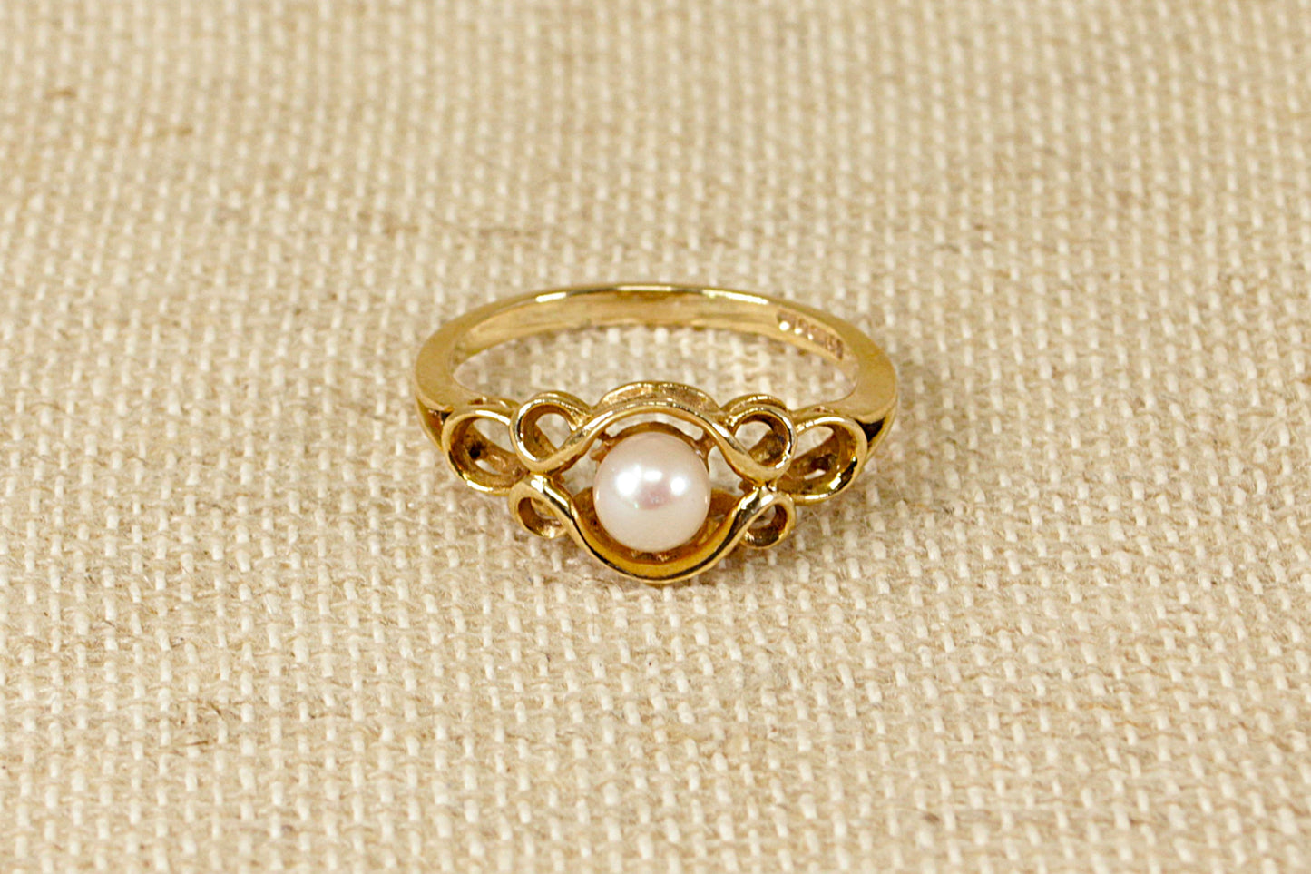 This beautiful and stylish ring has a single Pearl elegantly set in an intricate 9ct Gold setting. This vintage ring is in excellent condition, made in the traditional richness of yellow gold, inside the band it hallmarked for London 1990. UK Finger size: T.