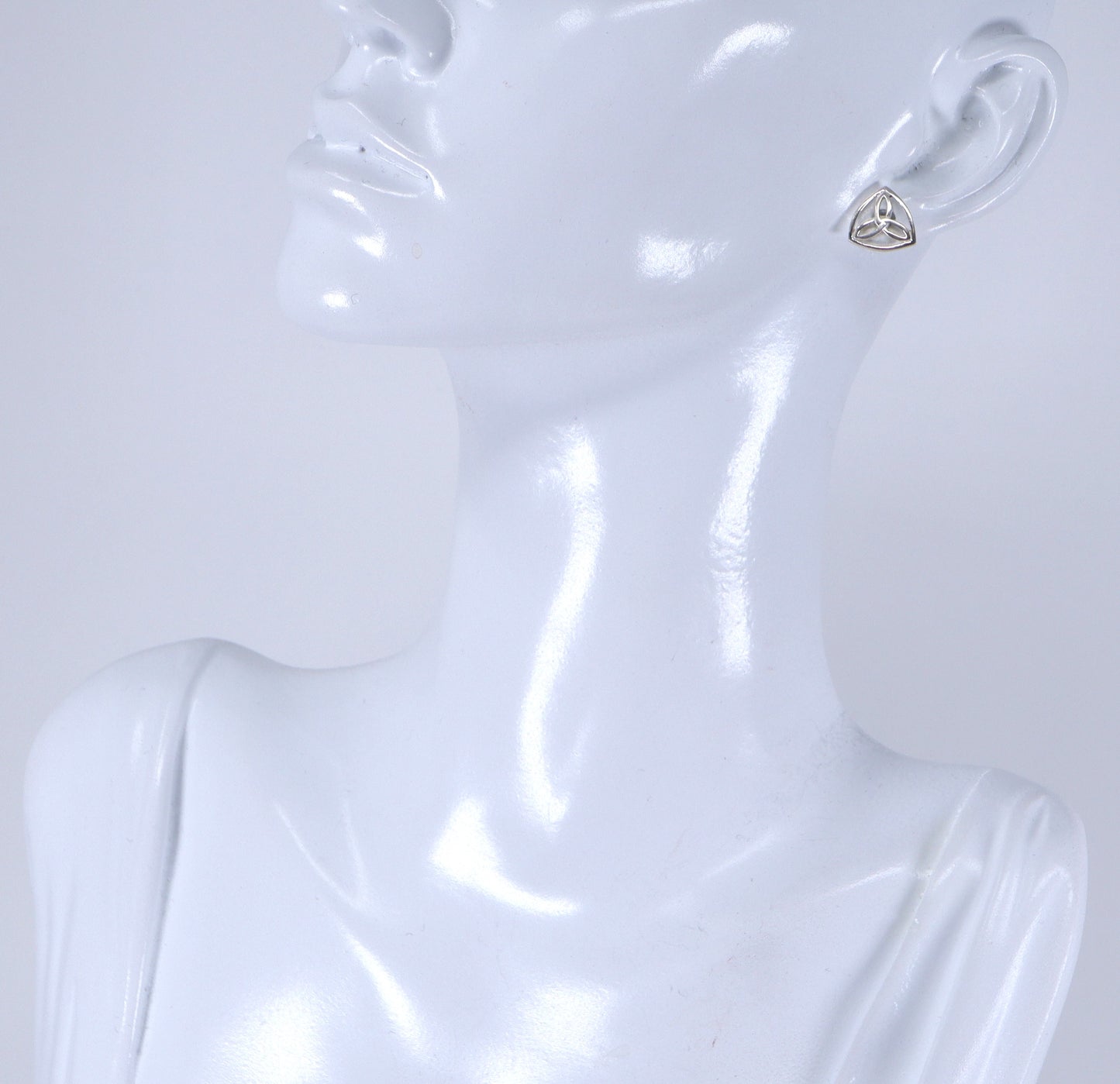 A pair of silver Celtic knot stud earrings displayed on a mannequin head.