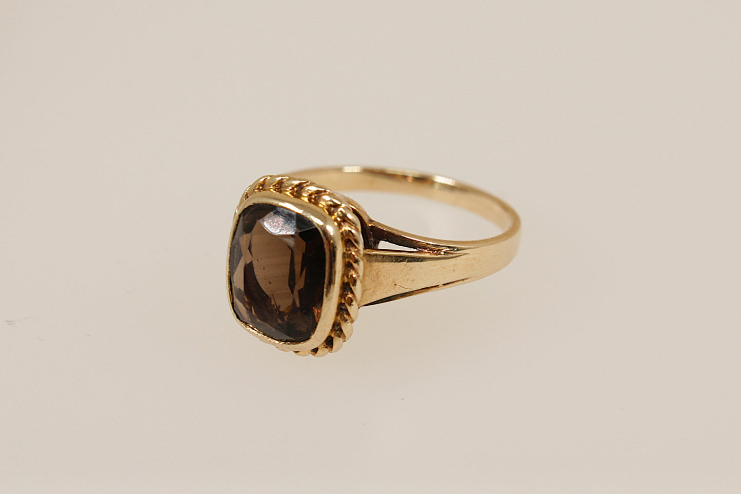 Gold ring with a smoky gemstone on a beige background