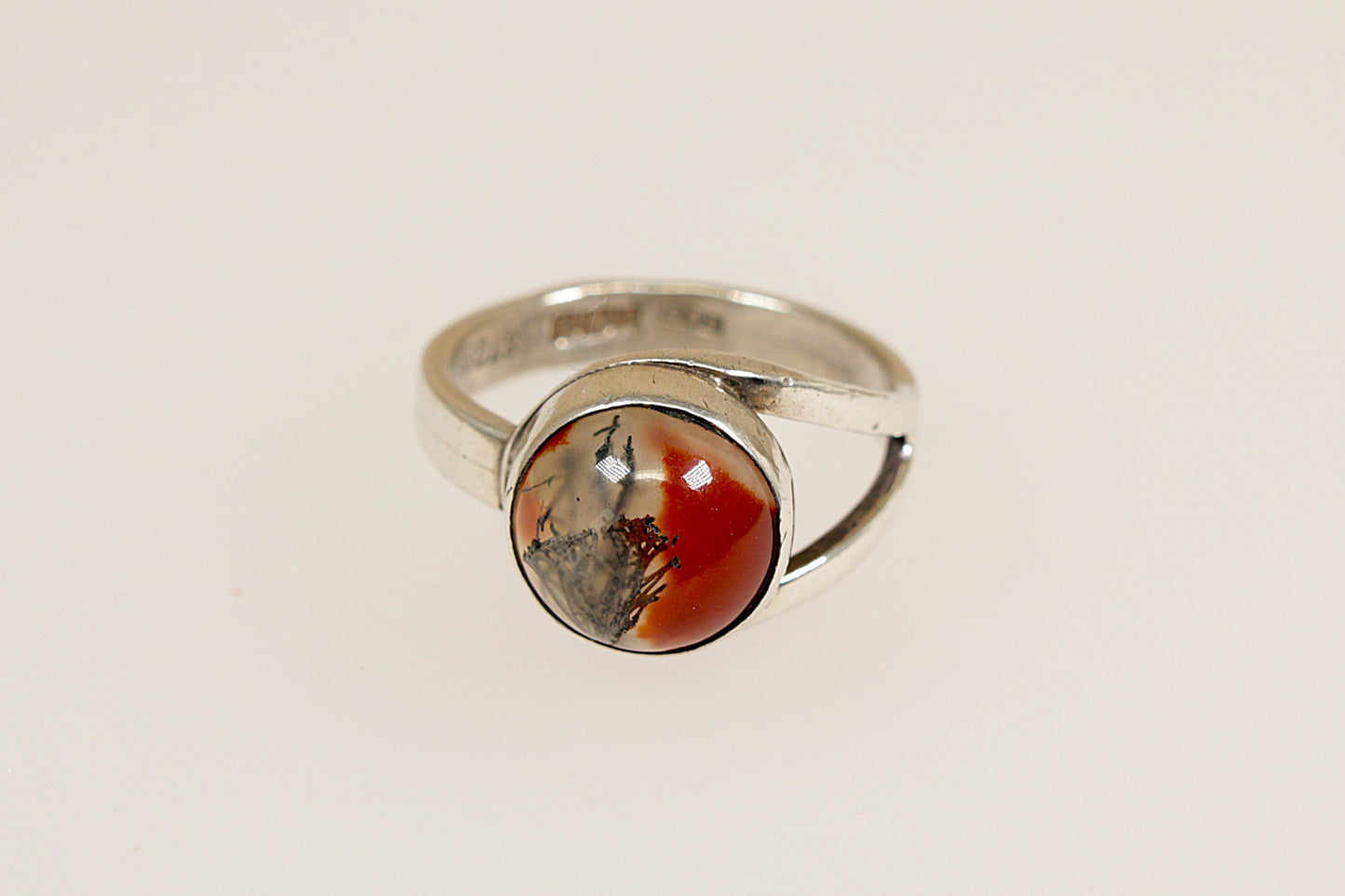 A vintage silver ring with a round Moss Agate stone displaying red, green, and brown colors, on a white background.