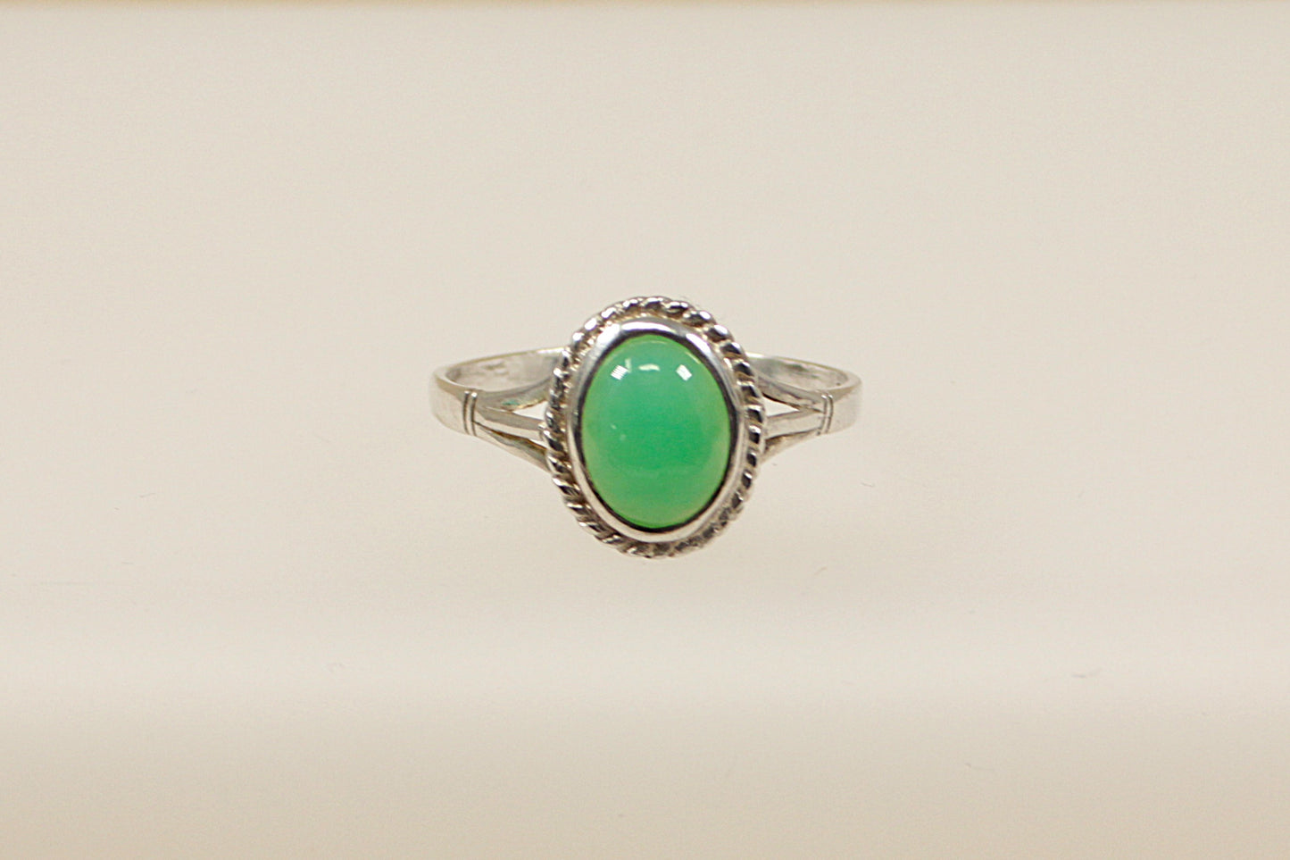 An oval cabochon chrysoprase gemstone set in a sterling silver ring with hallmarks visible inside the band.