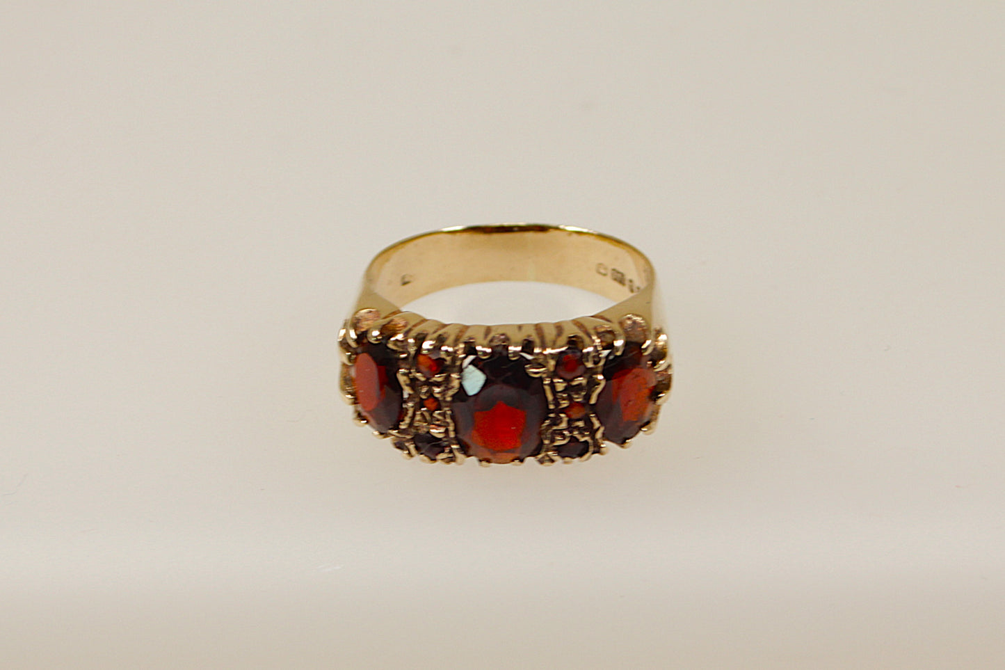 A vintage 9ct gold garnet ring with a classic design, featuring detailed filigree and milgrain patterns, and three prominent red garnets.