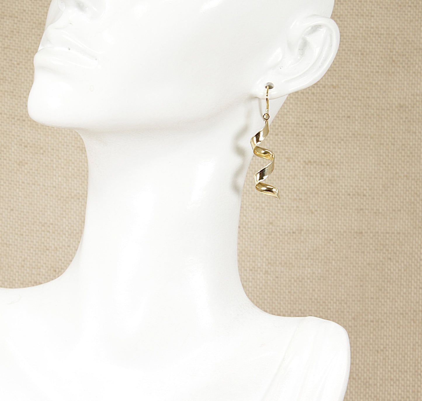 A pair of silver dropper earrings displayed on a mannequin head.
