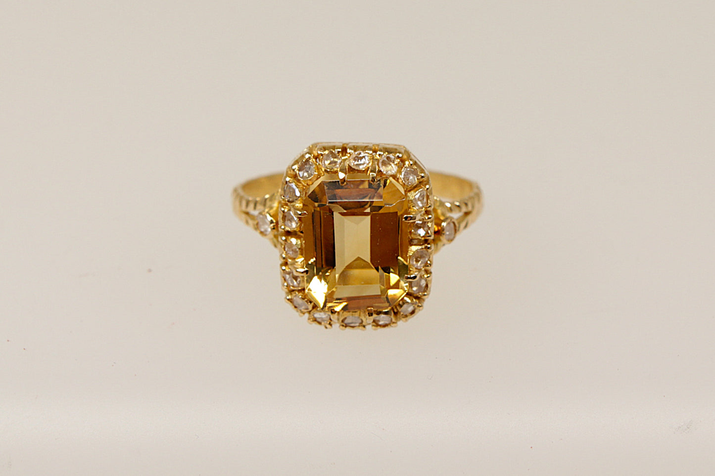 An 18ct gold ring with a central citrine gem surrounded by smaller diamonds, featuring intricate gold detailing on the band.