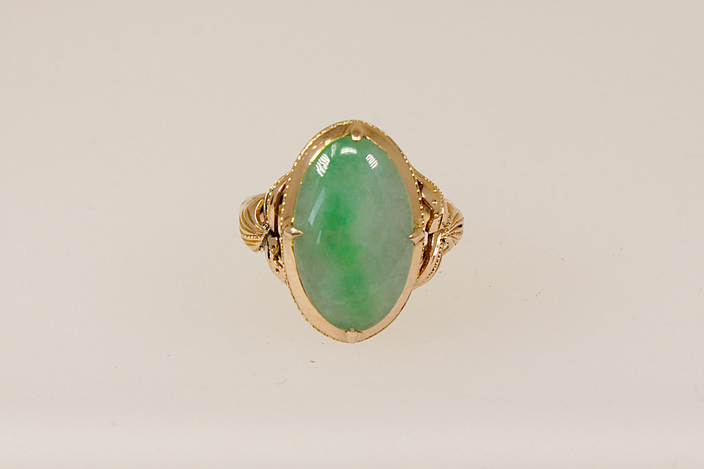 An oval-shaped jade cabochon ring set in a 14ct gold band with nature-inspired handcrafted goldwork.