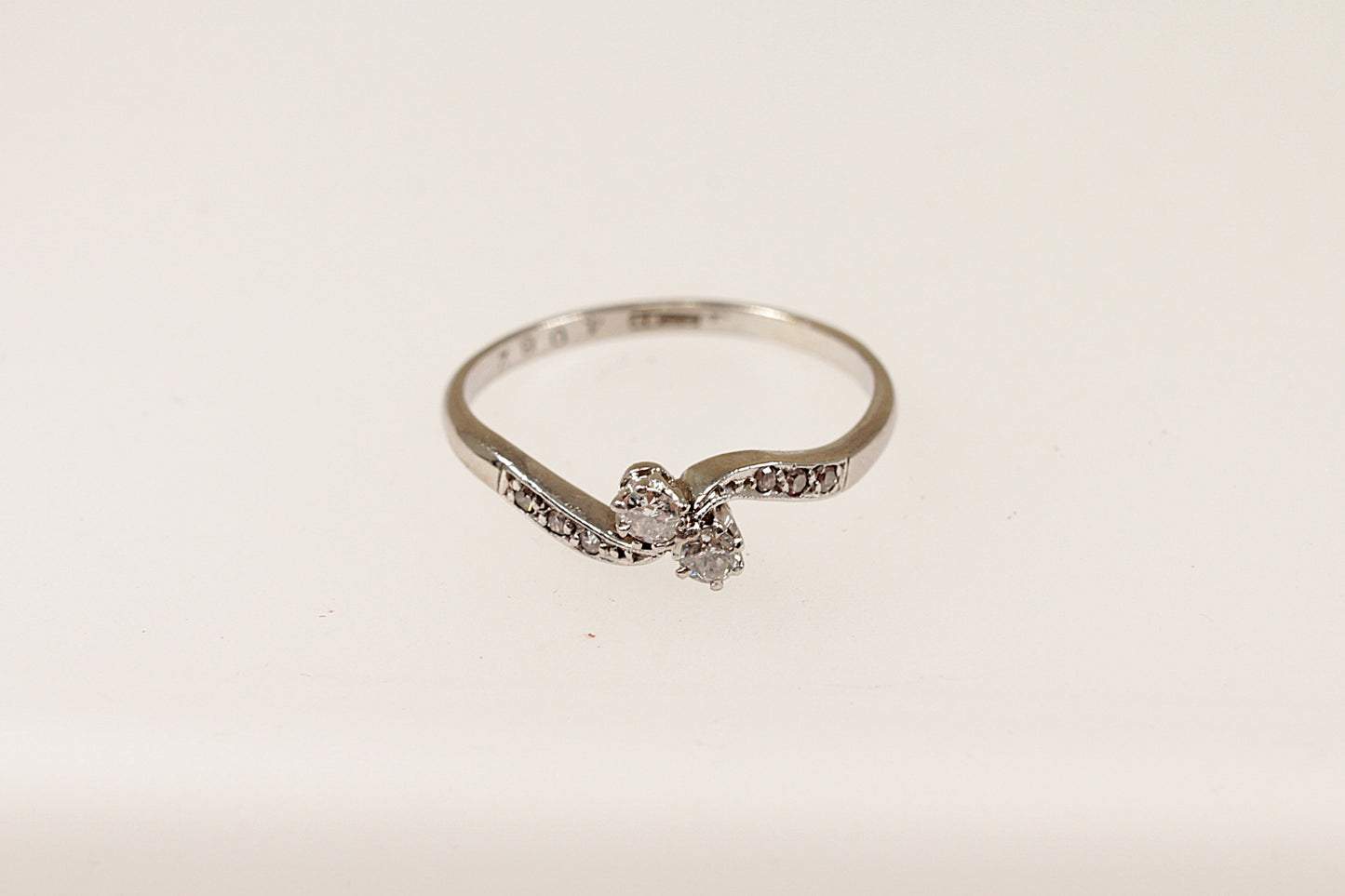 A vintage 18ct white gold and platinum diamond twist ring with a central pair of round diamonds and additional smaller diamonds on the shoulders, displayed against a white background.