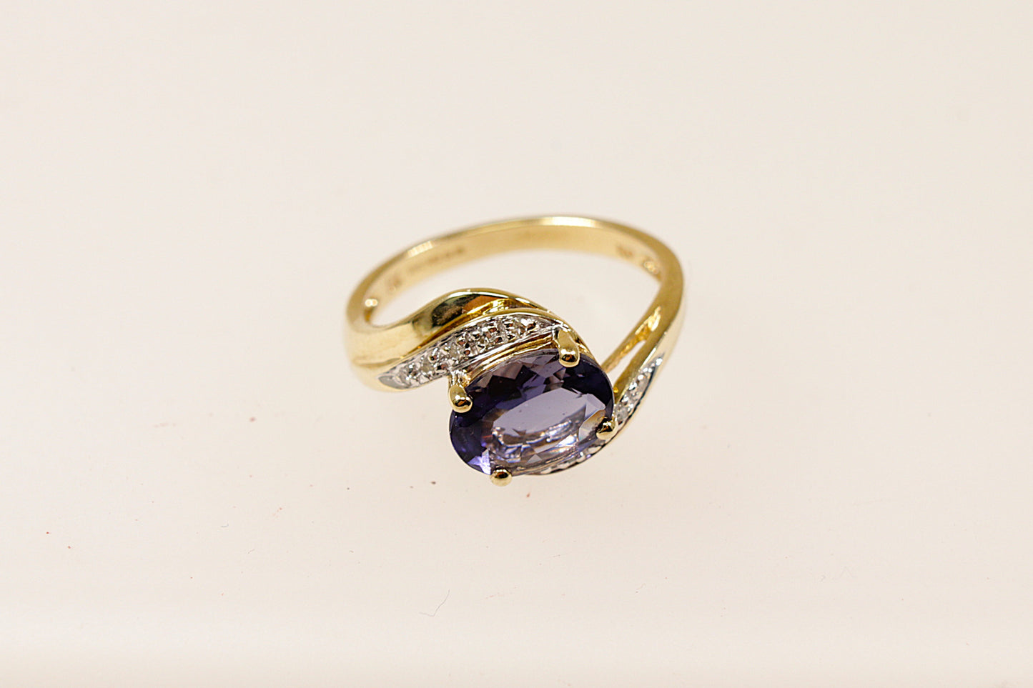 This 9ct Gold ring is a perfect blend of classic and contemporary design. The combination of the rich Iolite, shimmering Diamond accents, and the fluid twist design creates a piece that feels both timeless and distinctive. The centrepiece is the oval Blue Iolite that is claw set across the setting that gives a modern touch to the classic twist design. The Diamond accents are set along the twist. UK finger size M.