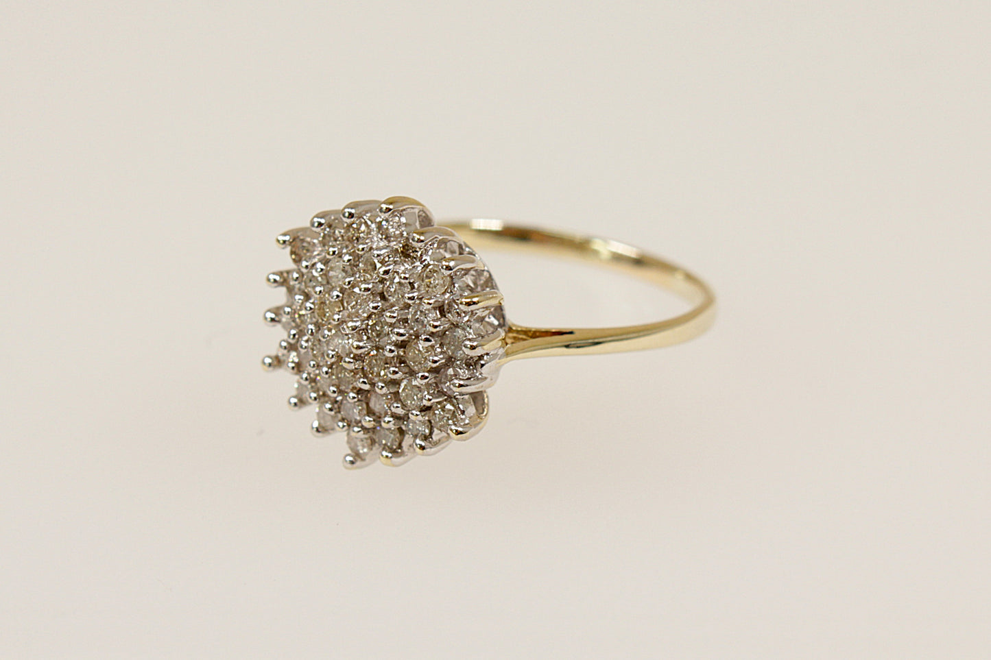 A 9ct gold diamond cluster ring with a high basket setting, showing a dome-shaped design with multiple diamonds arranged closely together. UK finger size L.