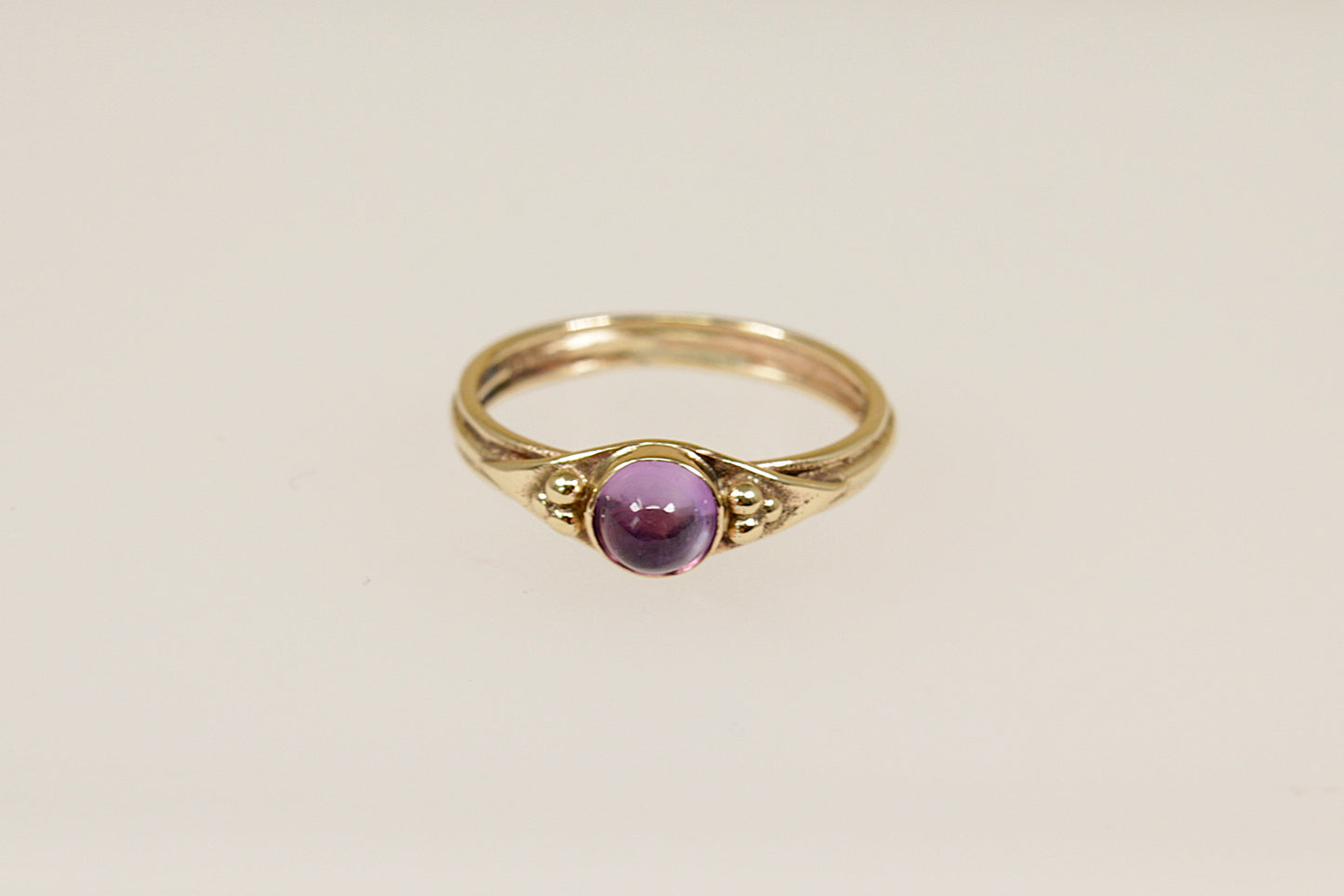 A vintage gold ring with a round amethyst cabochon gemstone set in a 9ct gold band with hallmarks interior.