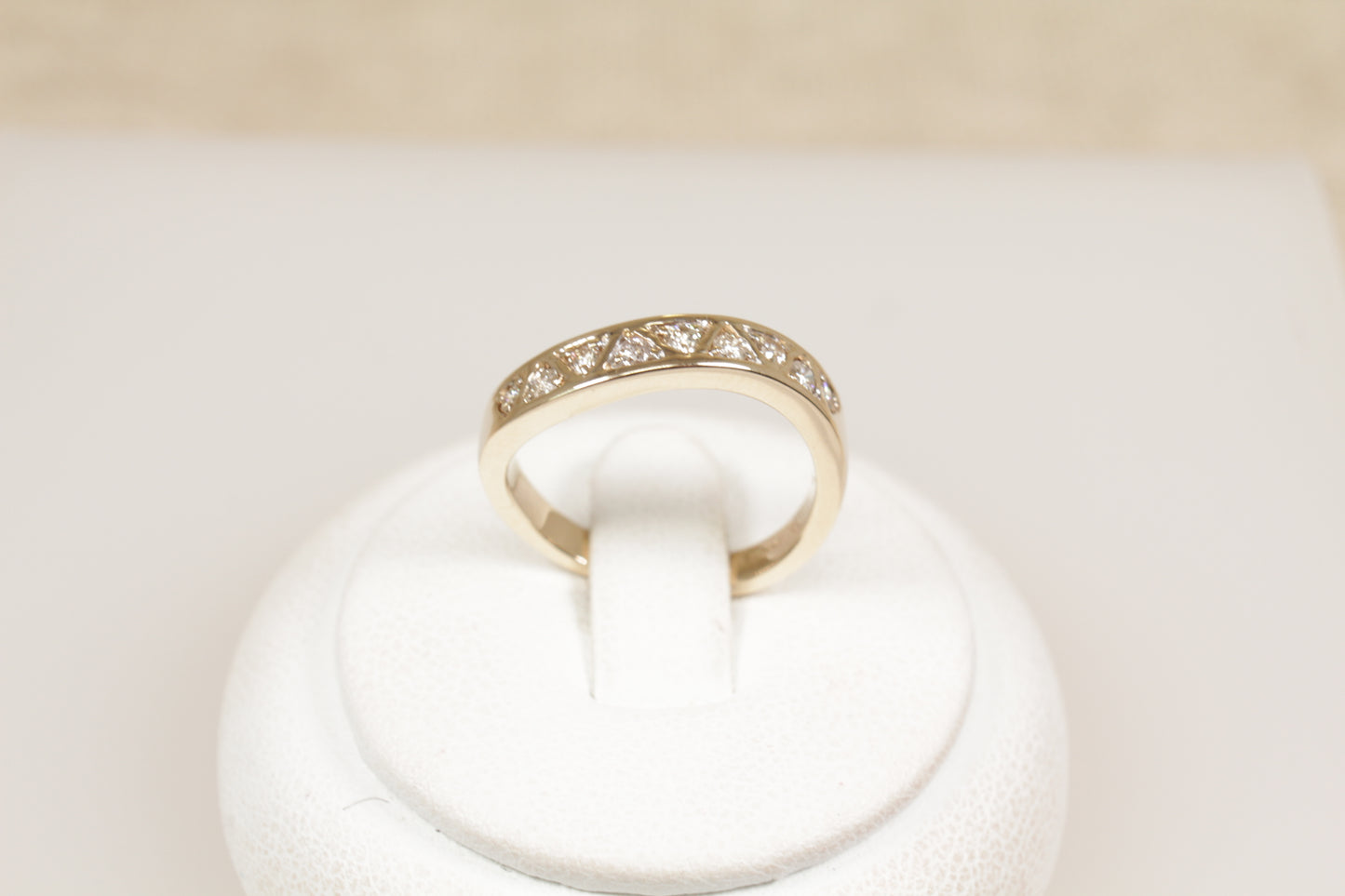 A 9ct gold diamond eternity ring displayed on a white mount, featuring triangular diamond formations and a wave effect band.