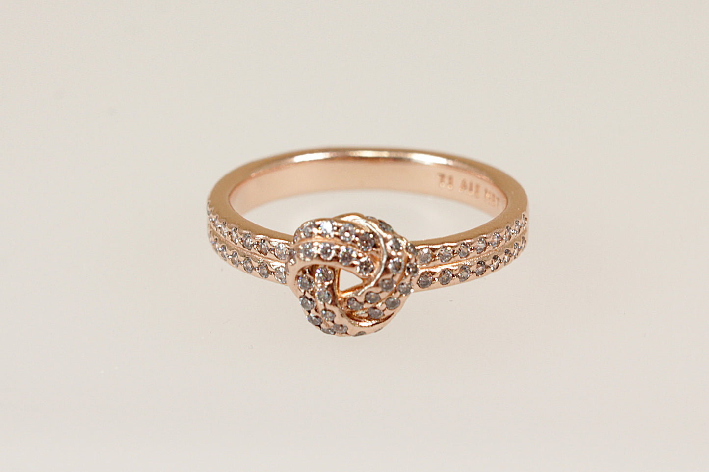 A Pandora Silver Gilt ring with a knot design, featuring Cubic Zirconia stones set in the knot and on the shoulders, displayed against a white background.