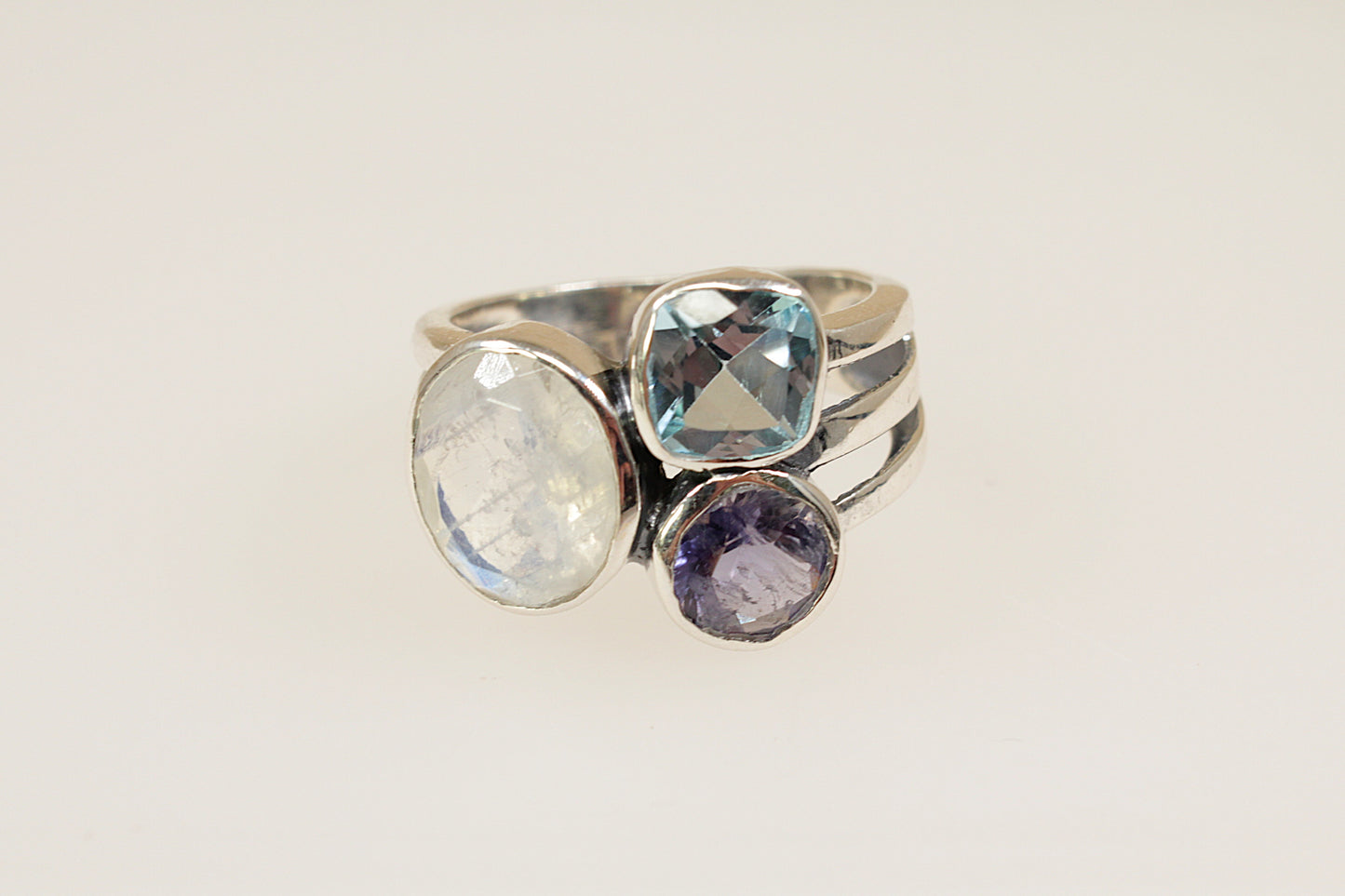 This Gorgeous Silver ring features 3 large faceted gemstones, Moonstone, Blue Iolite and Blue Topaz. Set in a stylish and elegant split band design, it is a bold and artistic statement piece. UK Finger size P.