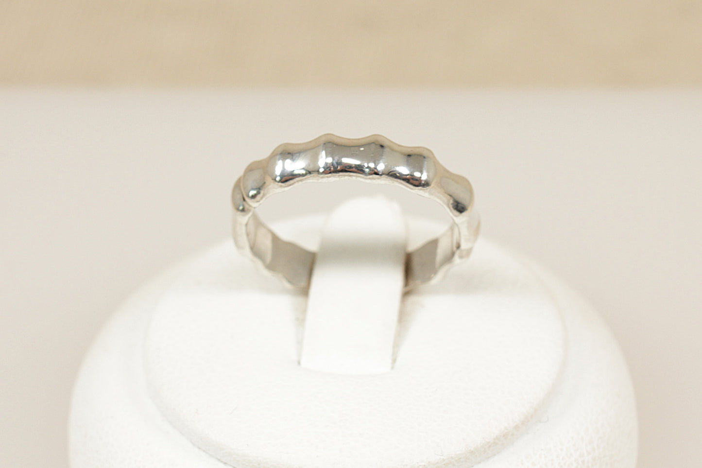 Silver ring on a white cushion with a beige background