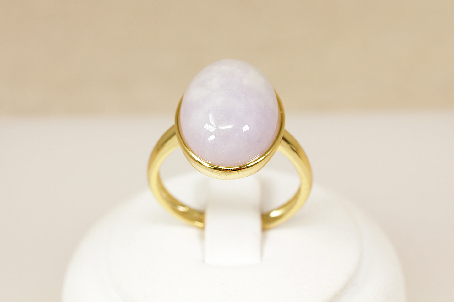 Gold ring with a white stone on a beige background
