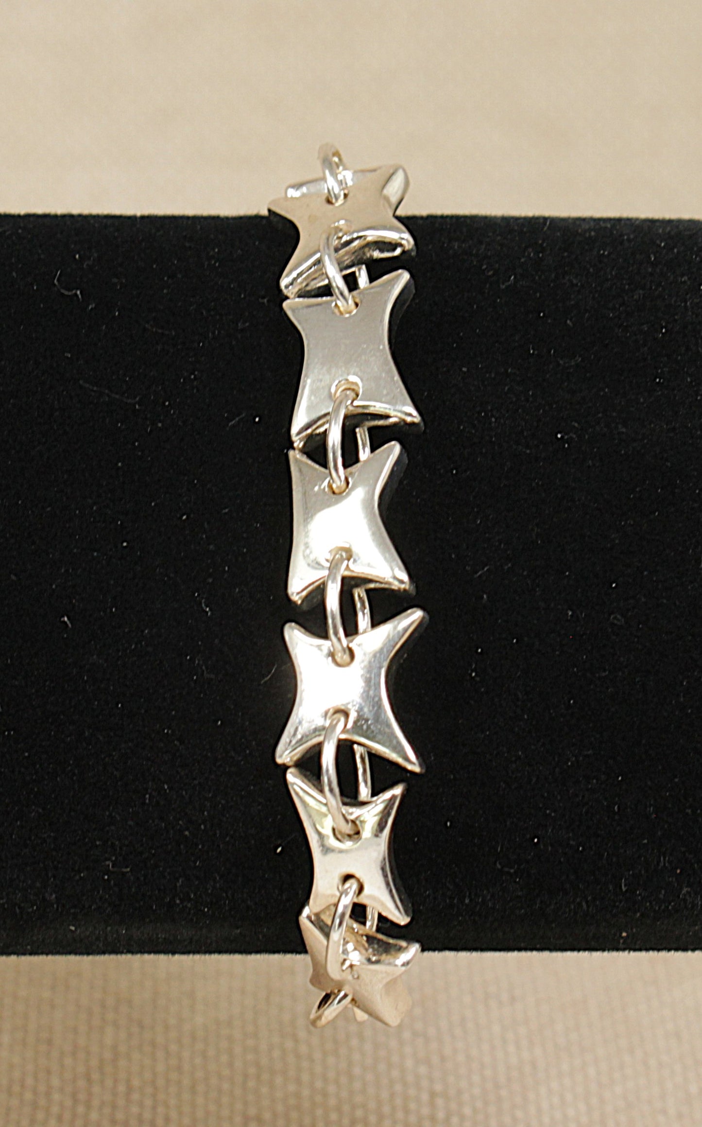 Silver star-shaped bracelet on a black and beige background