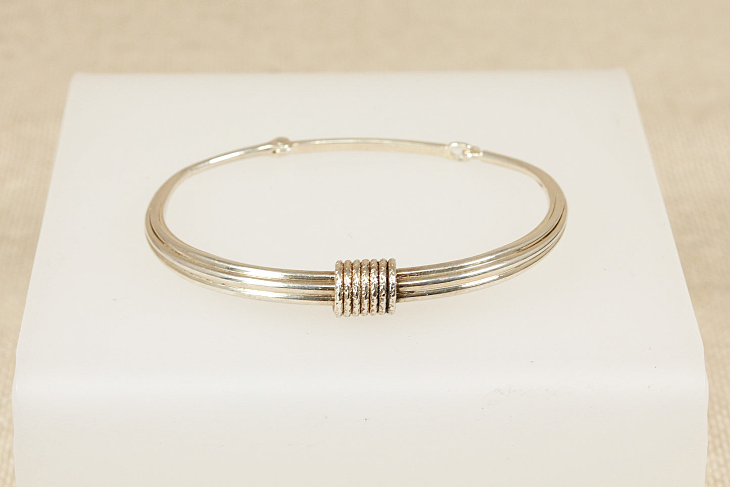 Silver bracelet on a white box with a beige background