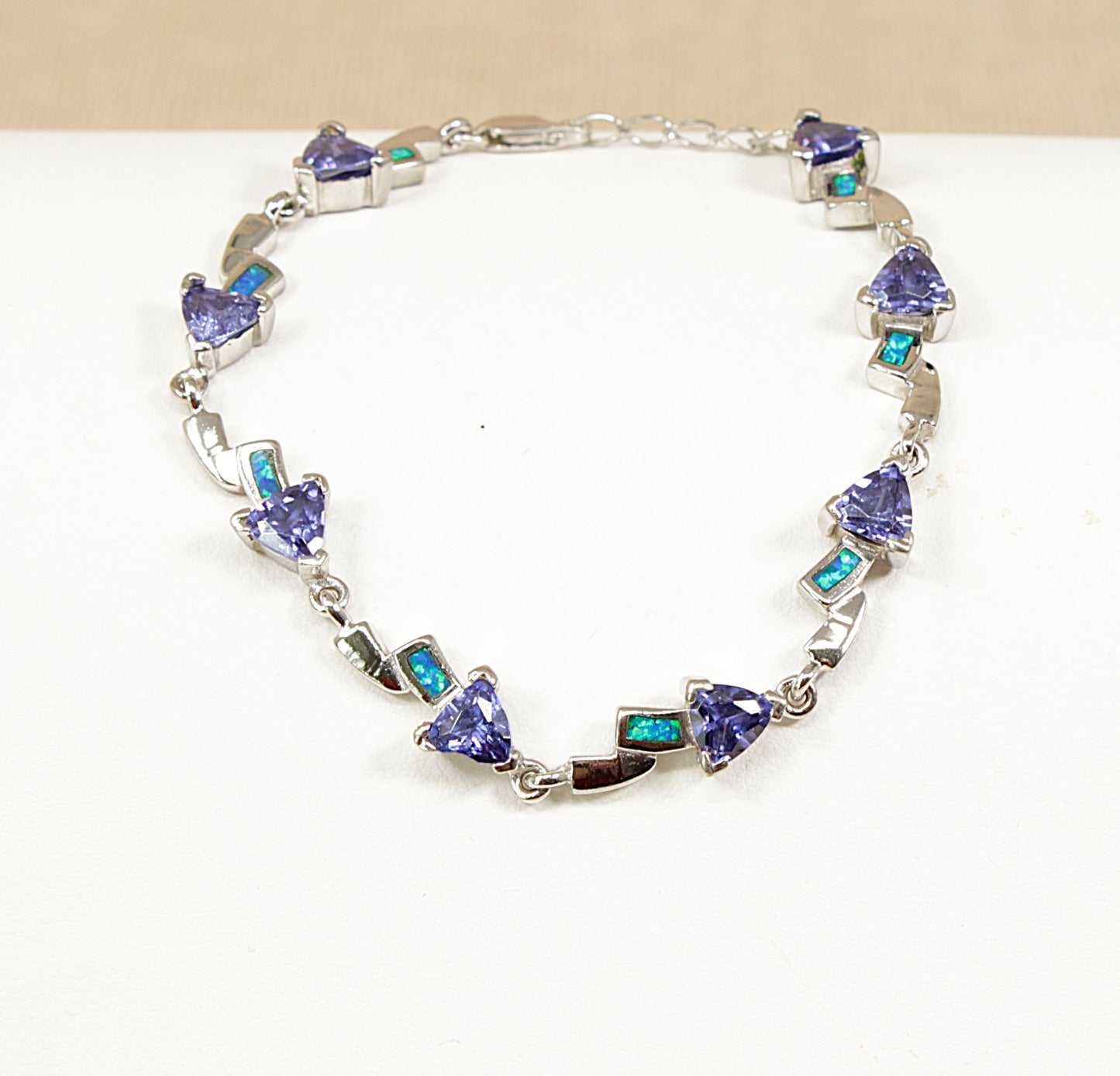 Silver bracelet with opal and heart-shaped blue gemstones on a white background