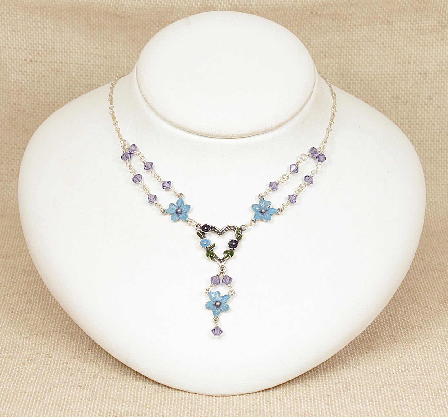 Necklace with floral designs on a white stand against a beige background