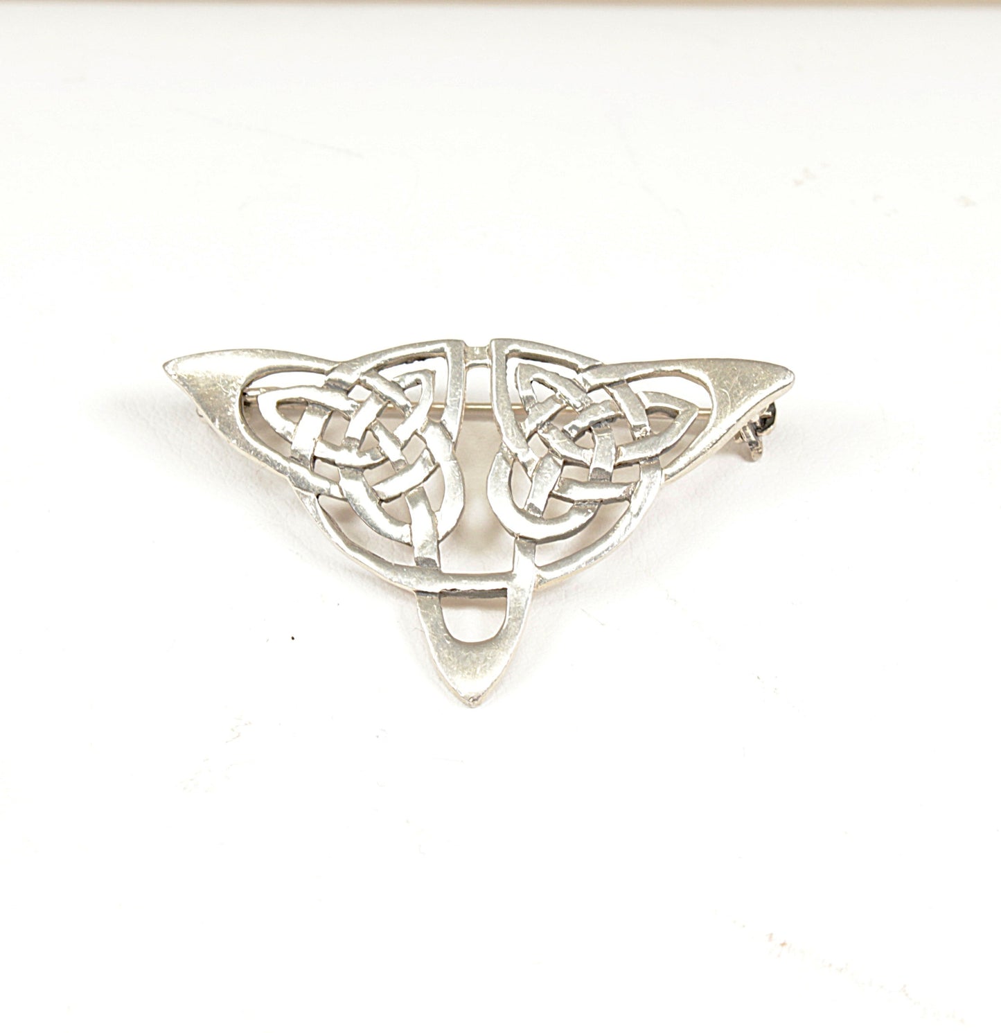 Silver Celtic knot brooch on a white background