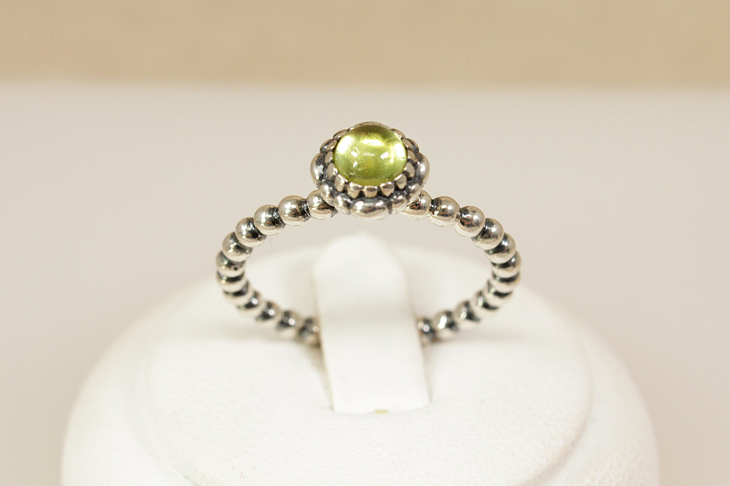 Silver Pandora ring with a peridot gemstone on a white background