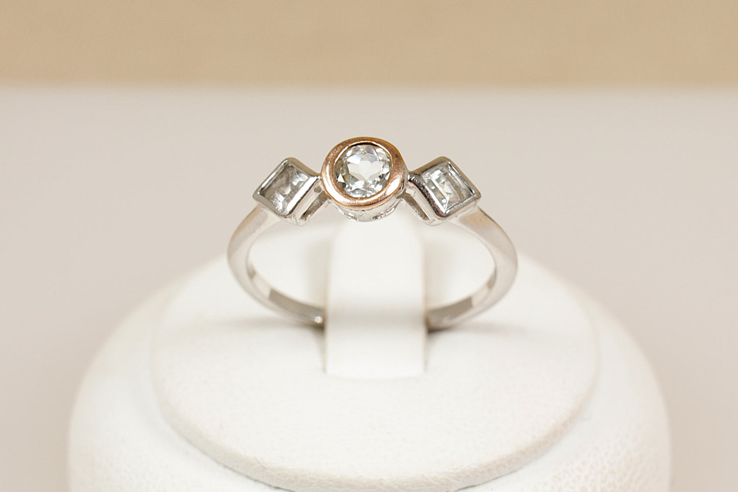 Clogau trilogy ring on a white stand with a beige background