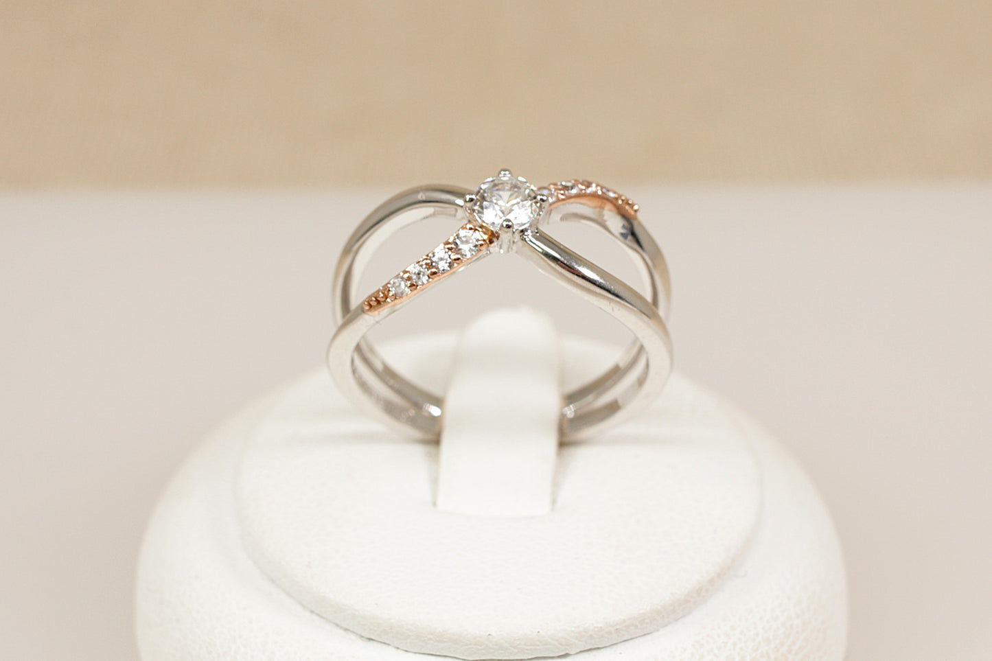 Silver Clogau Kiss Ring ring with a topaz on a white cushion against a beige background