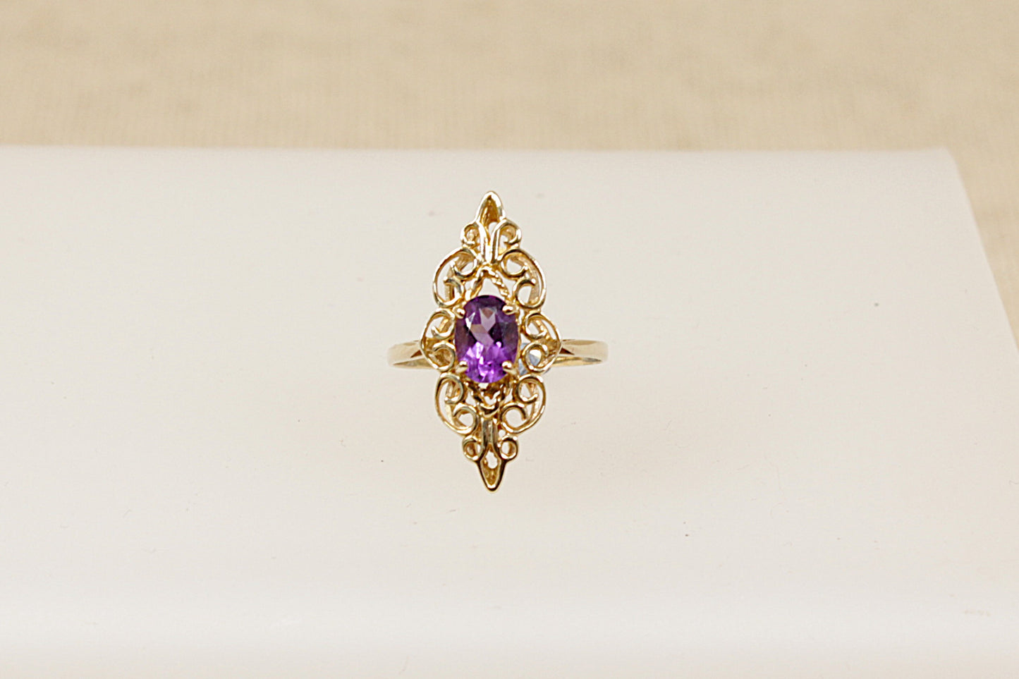 A 9ct gold ornate navette-shaped ring with a deep purple oval Amethyst gemstone, It is in excellent condition and inside the band it has Sheffield Hallmarks for 9ct gold. UK Finger size O.