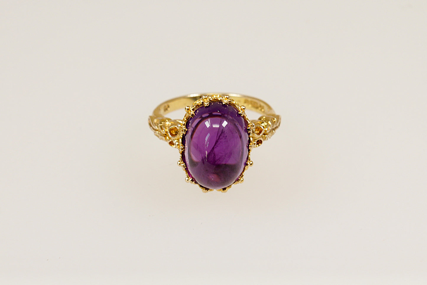 This 9ct Gold ring is a truly magnificent vintage statement with regal presence!
It features a large, high-domed oval cabochon Amethyst with a deep purple colour, set in an intricate gold basket crown setting. UK finger size P.
