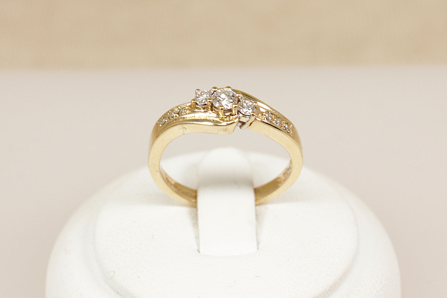 A timeless and graceful 9ct gold Diamond ring, featuring a classic trilogy twist design. At its centre are three sparkling diamonds set in a gentle twist, symbolizing the past, present, and future. Each shoulder is adorned with three smaller diamond accents, adding extra brilliance and elegance to the design, UK finger size N.