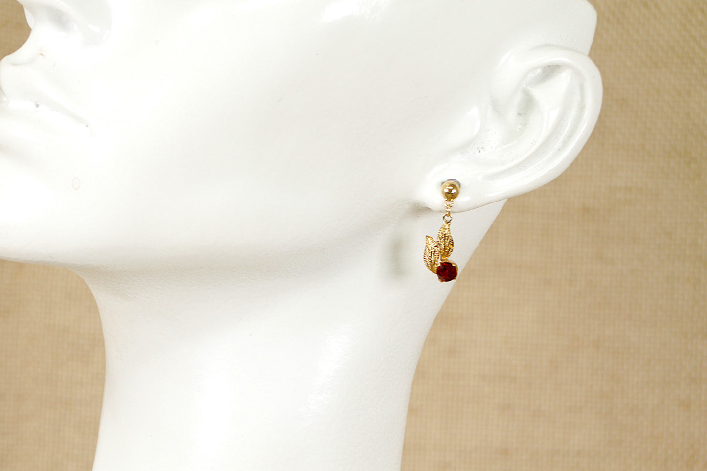 A pair of 9ct gold garnet stud drop earrings with a leaf design setting. Drop length: 20 mm.