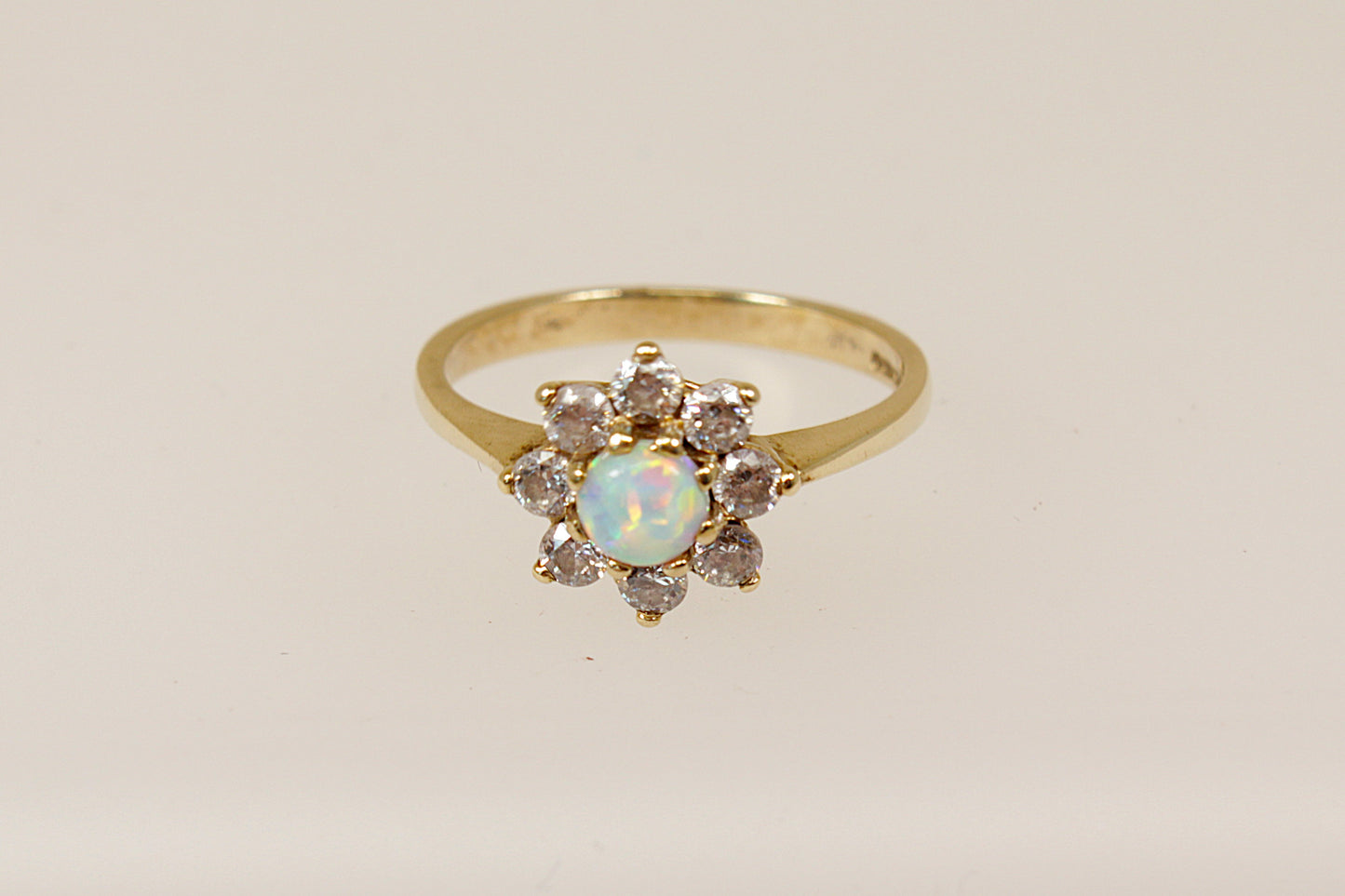 A 9ct gold daisy ring with a central opal surrounded by white crystals, displayed against a white background.