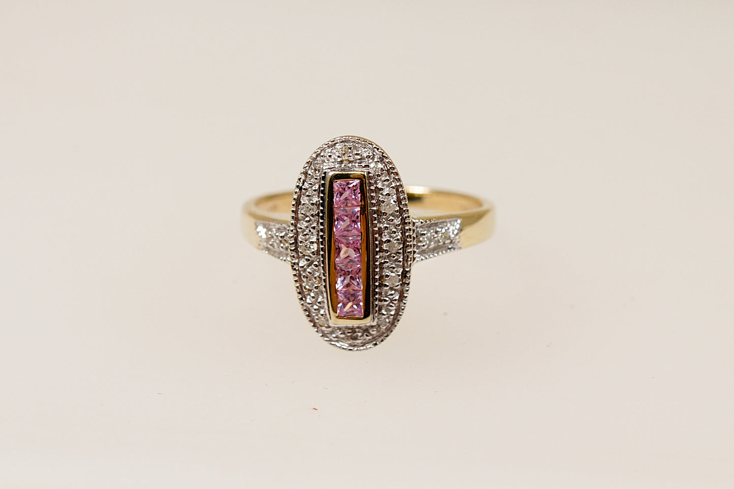 A 9ct gold ring with a vertical arrangement of pink sapphire stones and diamond accents around the oval design and on the shoulders.