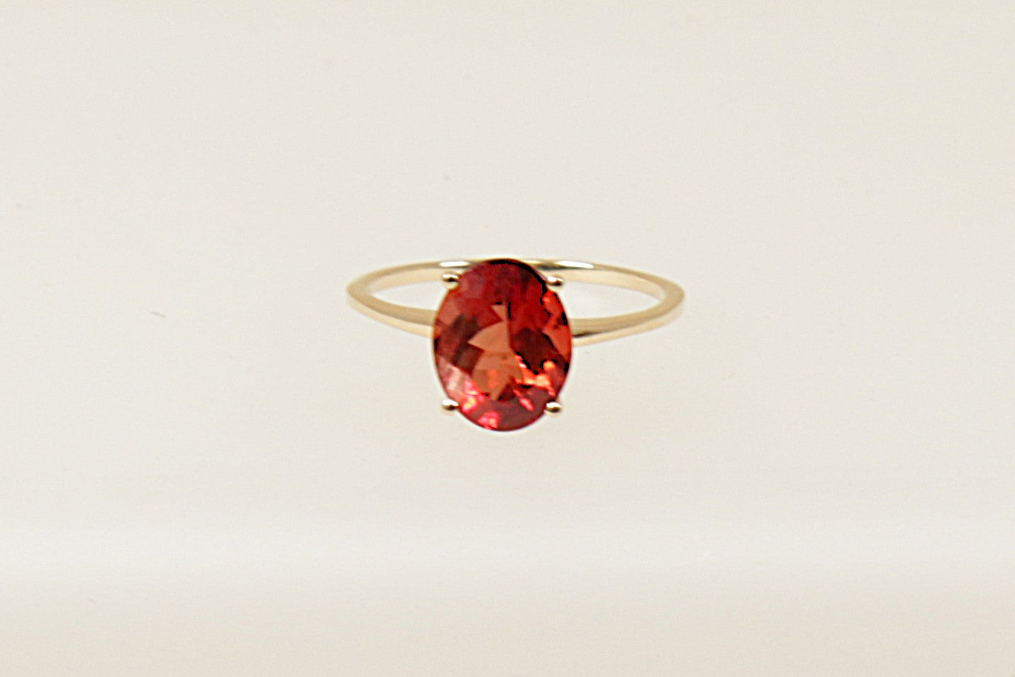 A 9ct gold solitaire ring with an oval rhodolite garnet colored crystal, displayed against a white background.