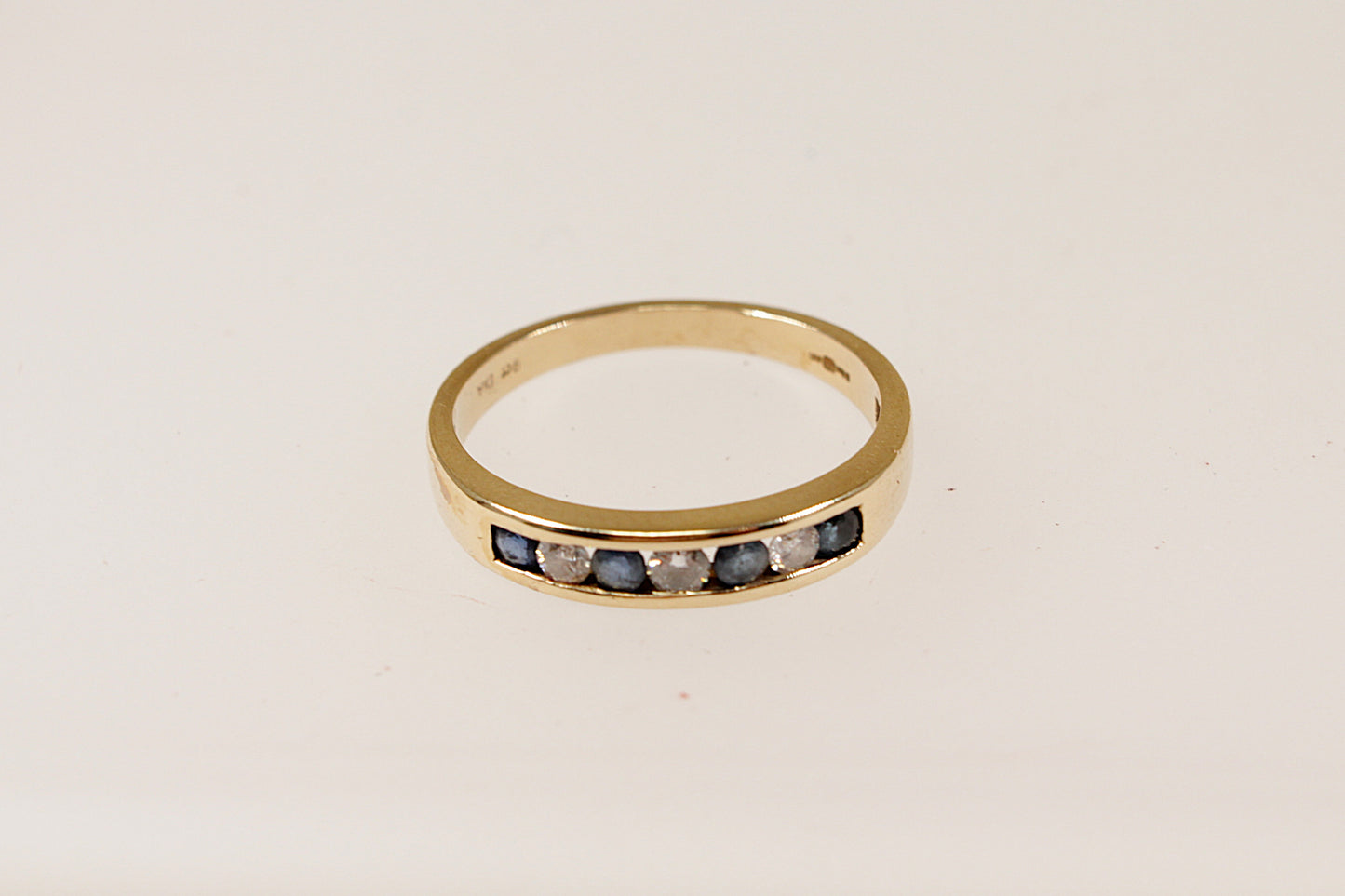 9ct yellow gold channel set blue sapphire and diamond band ring, UK finger size N.