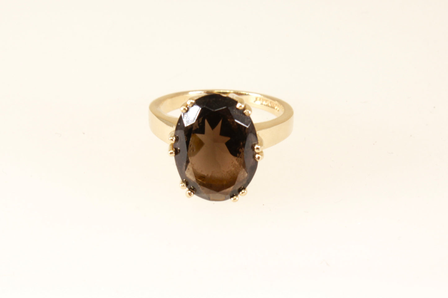 A 9ct gold solitaire ring with a smokey quartz oval stone, displayed against a white background.