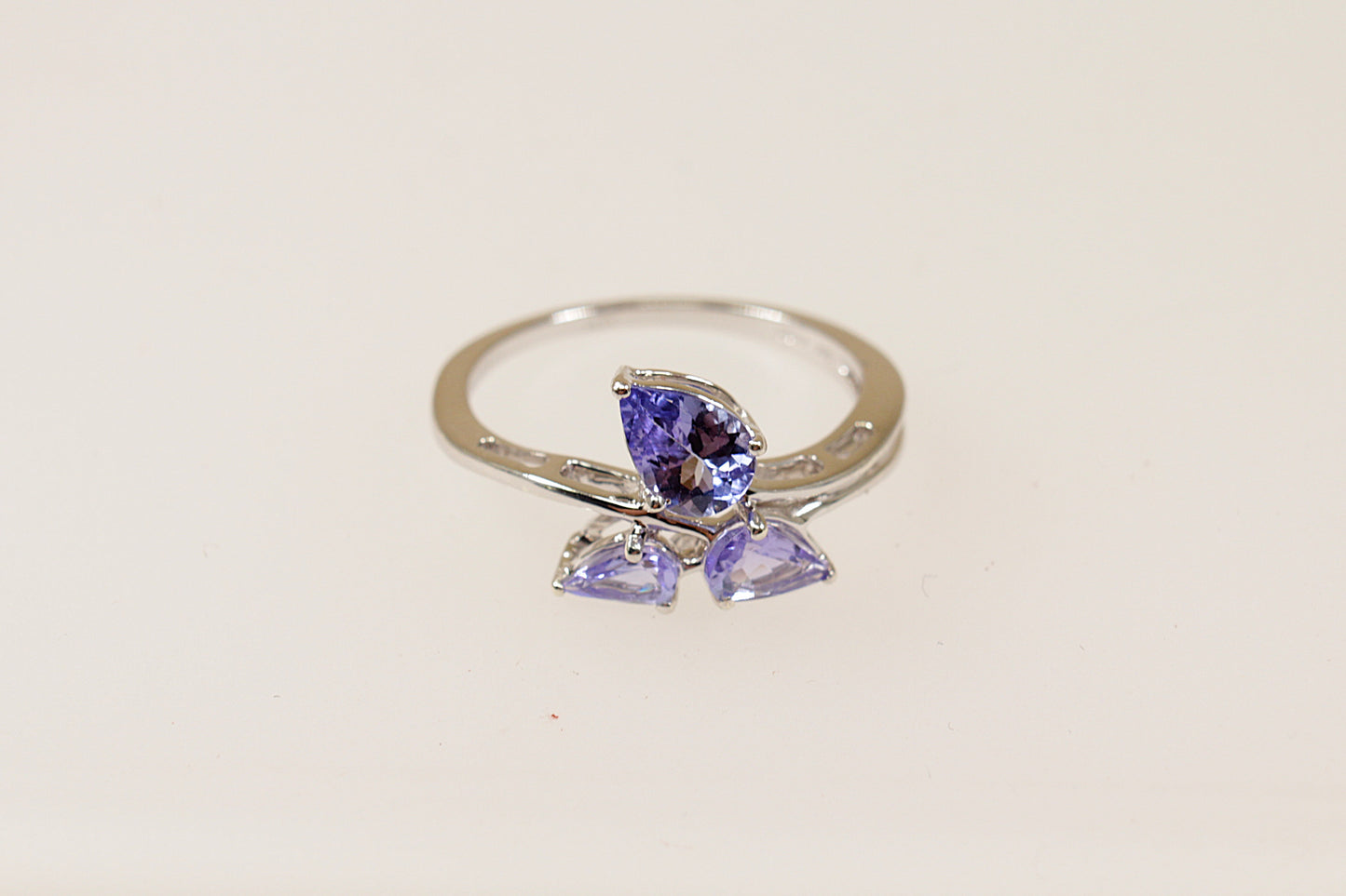 A 9ct white gold ring with three pear cut blue iolite gemstones arranged in an offset pattern to form the petals of a flower.