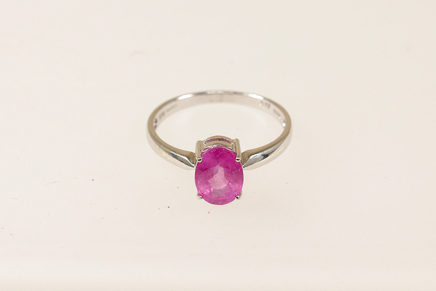 A 9ct white gold ring with an oval pink Sapphire centerpiece, displayed against a white background.