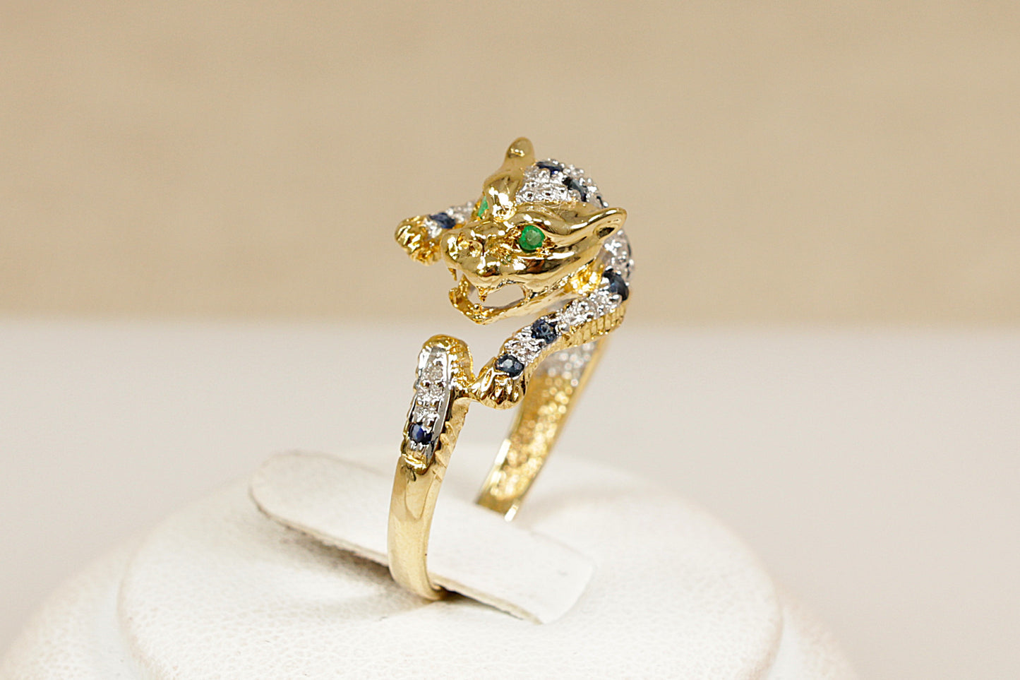 A 18ct yellow gold custom designed ring in the shape of a roaring leopard wild cat its body is encrusted with white gold, sapphires and diamonds the leopard has green emerald eyes UK finger size M.