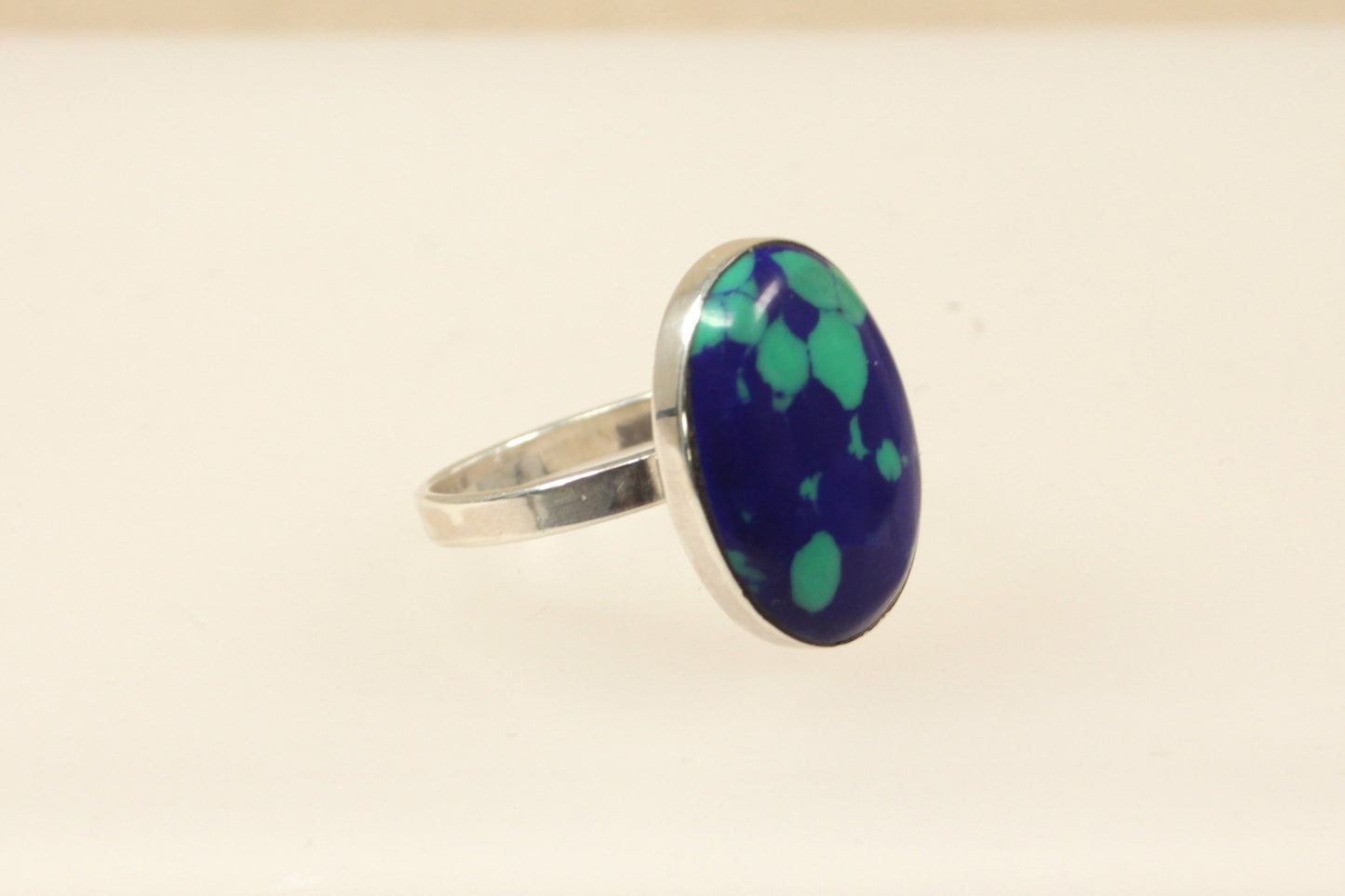 An oval blue spotted design ring with a sterling silver setting.