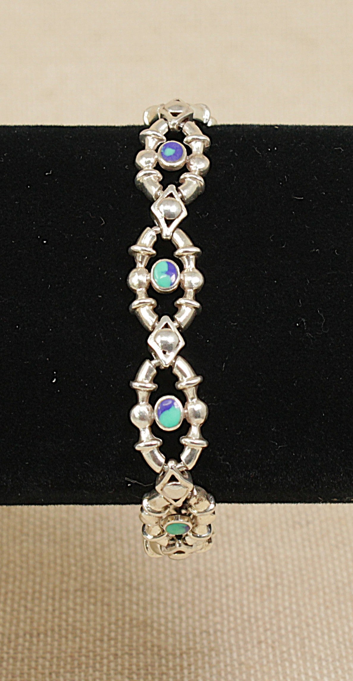 Silver bracelet-with blue green detail on a black and beige background