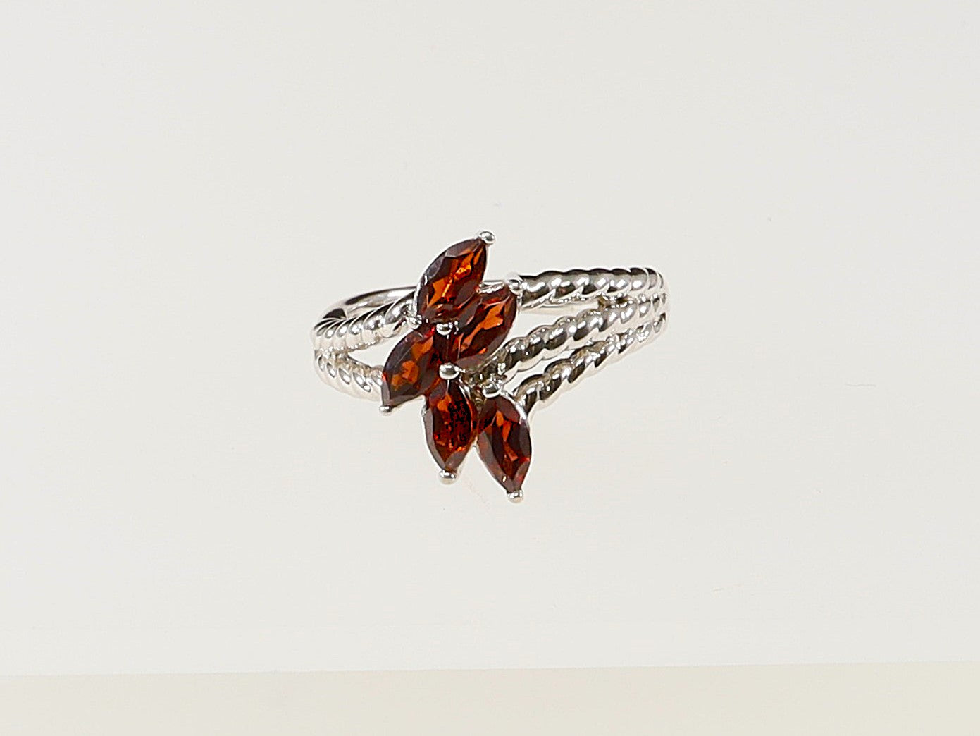A silver ring with five garnet-colored crystals arranged in a flower pattern.