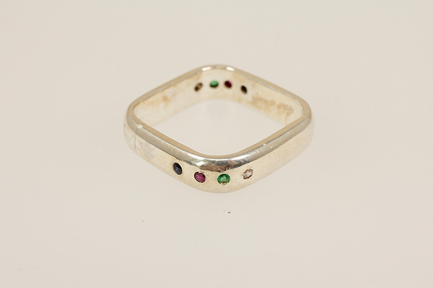 Sterling silver ring with colored gemstones on a beige background