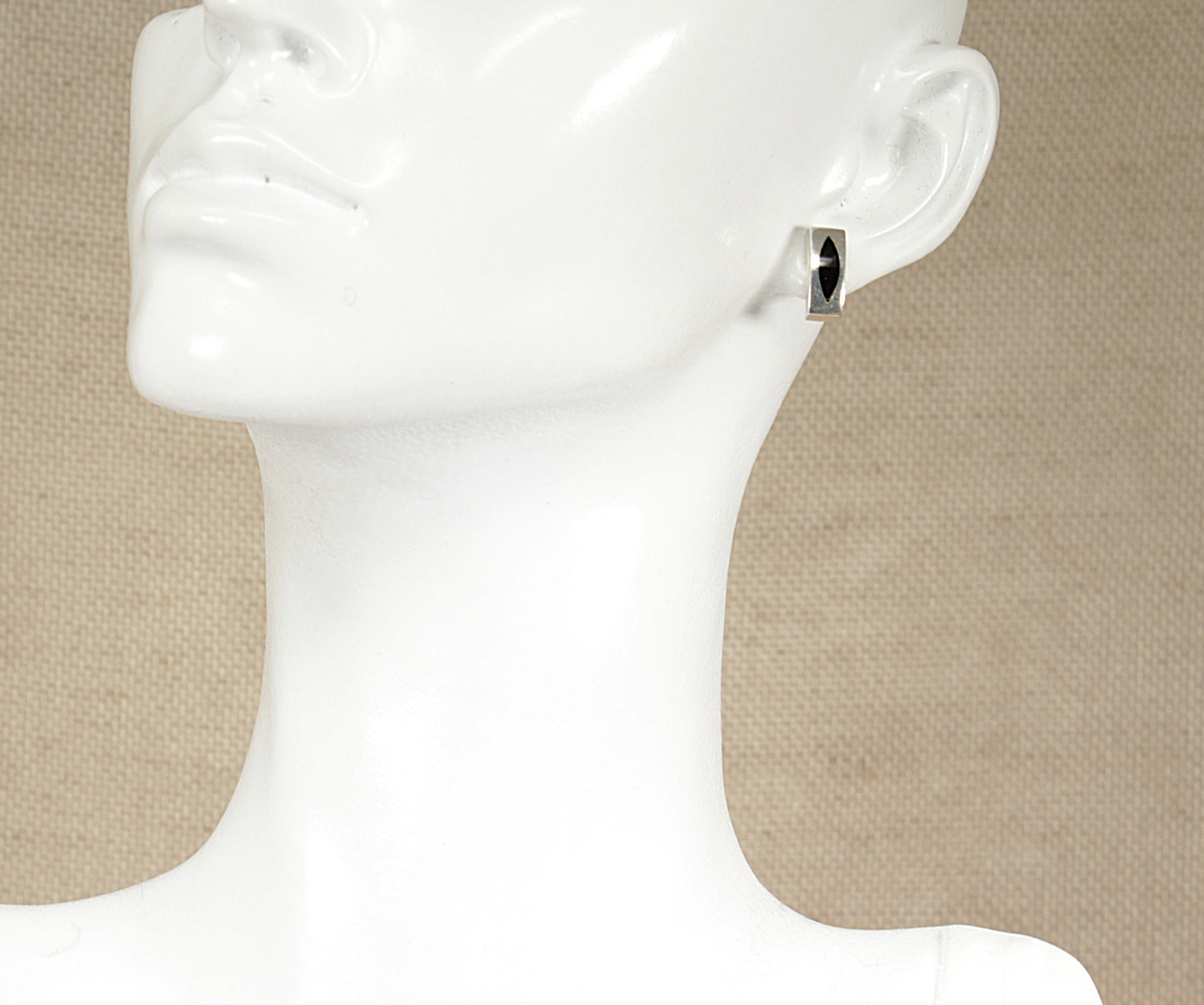 A silver onyx stud earring displayed on a mannequin head.