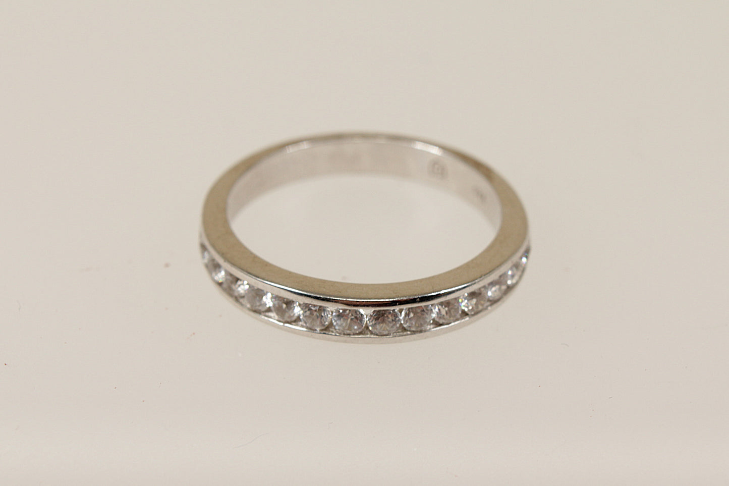 A silver white topaz half eternity ring with channel setting, displayed against a white background.