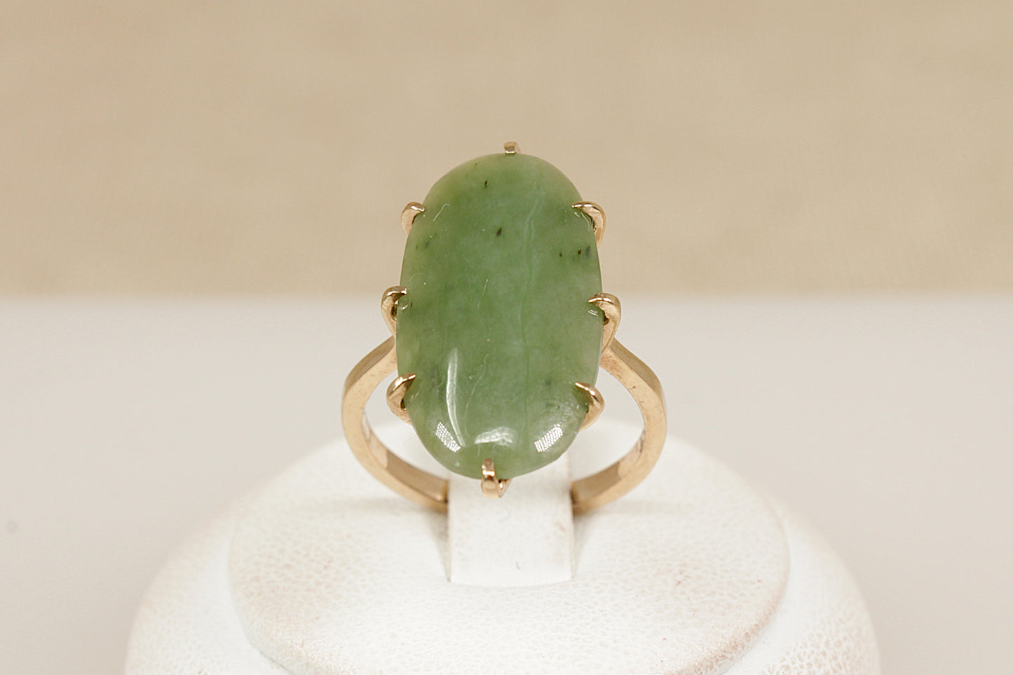 A graceful vintage ring crafted in solid 9ct yellow gold, showcasing a striking navette-shaped Jadeite cabochon. The smooth, polished surface of the Jadeite is gently domed, with natural inclusions visible—typical of authentic, untreated jadeite and adding to its organic charm. The inside of the band is stamped ‘9ct’, UK finger size N.