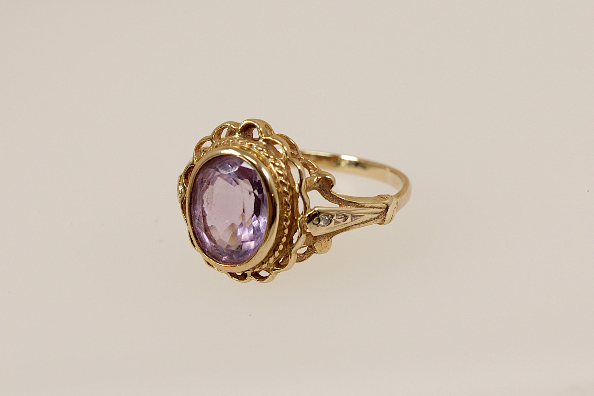 Gold ring with a purple gemstone on a beige background