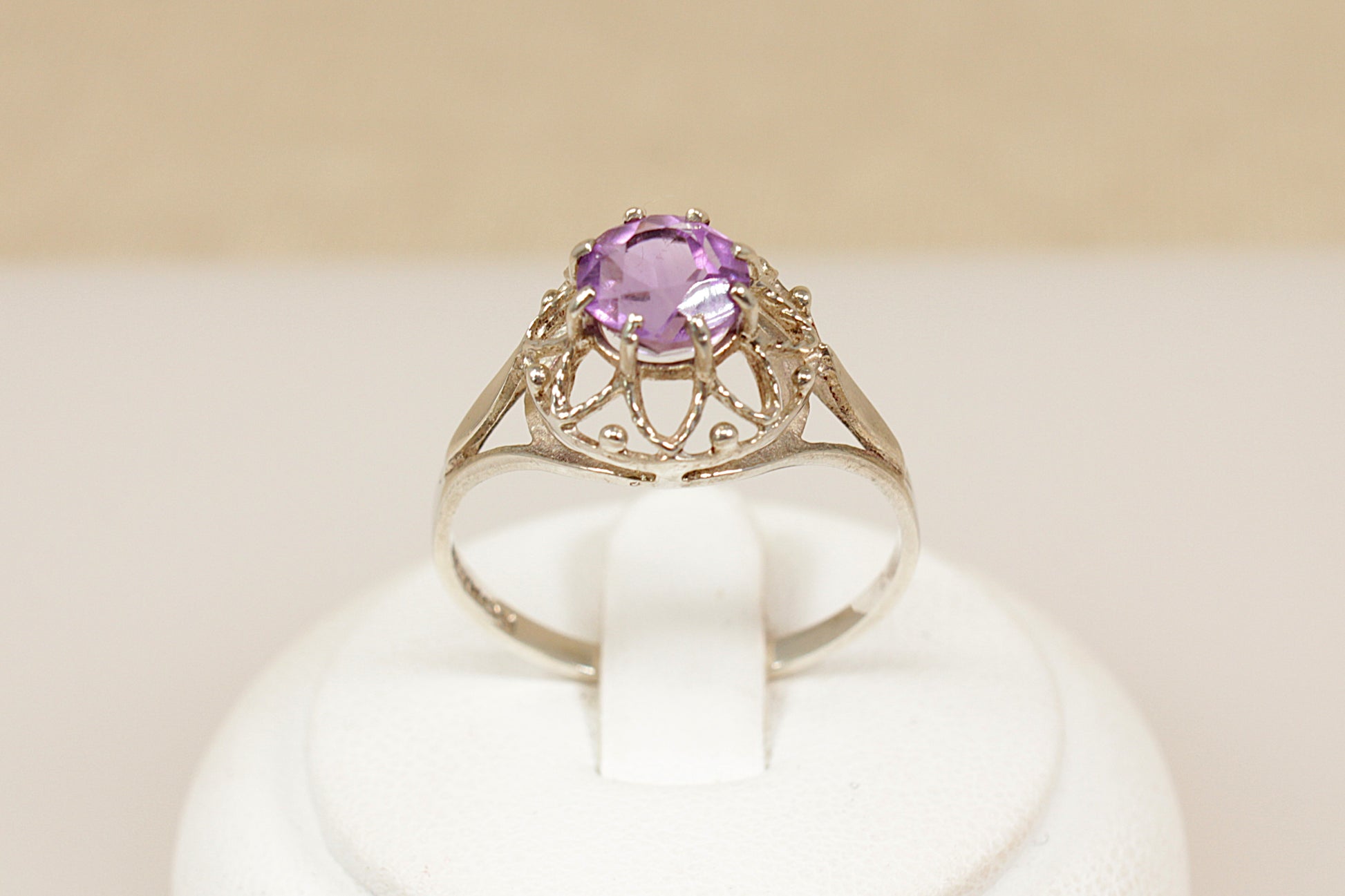 Gold ring with a purple gemstone on a white cushion