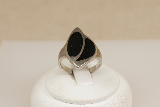 Silver statement ring with black inlay on a white display stand with a beige background