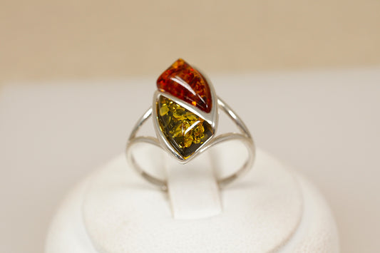 Ring with a multicolored amber gemstone on a white stand against a beige background